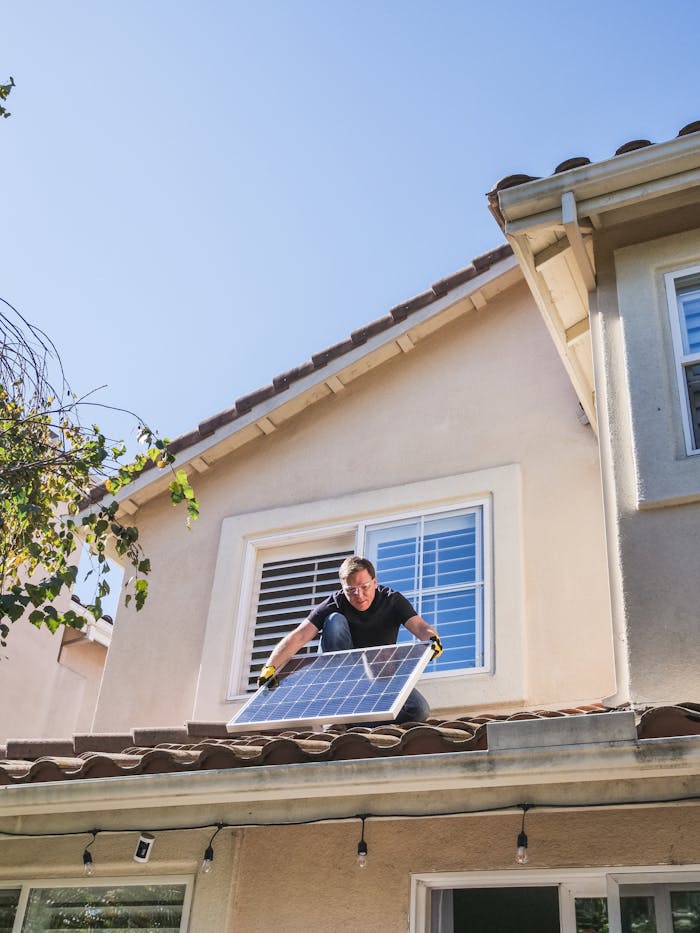 hero-img-01 A worker installs a solar panel on a residential rooftop, showcasing renewable energy technology.