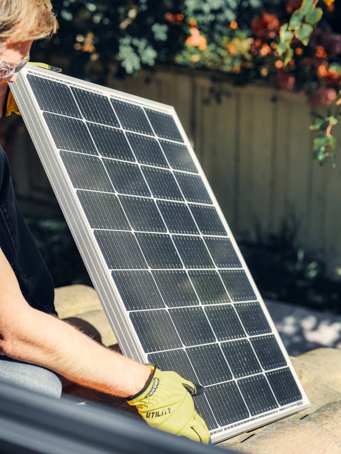 hero-img-02 A worker installs a solar panel in a garden, promoting clean energy.